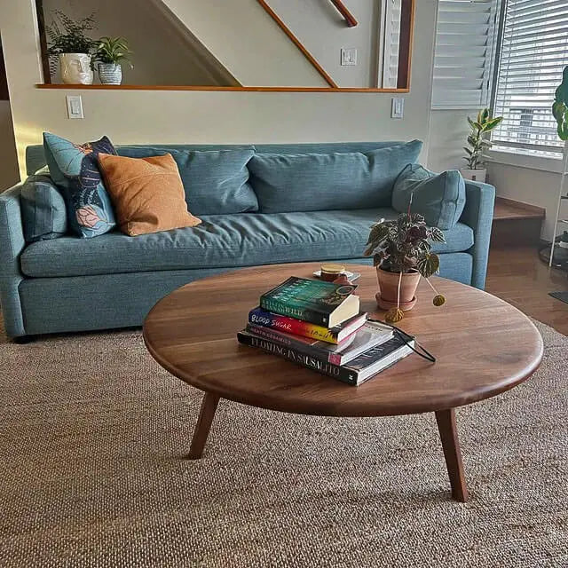 Customer photo featuring the Sidney Solid Wood Mid-Century Round Coffee Table placed in front of a stylish couch, showcasing its elegant design and rich walnut wood finish in a cozy living room setting.