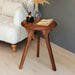 Main picture of the side table with decor on it next to a armchair