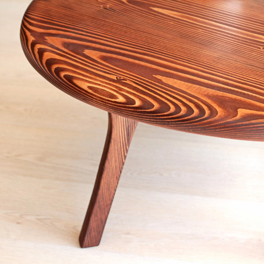 The Solid Pine Wood Mid Century Round Coffee Table placed in a living room setting, complementing modern décor with its warm wood tones.