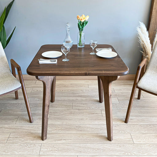  A top-down view of the Sidney Mid-Century square dining table, showcasing its sleek, minimalist design and smooth wooden finish.