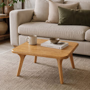 Sidney Square Wood Coffee Table Solid Oak Wood – Mid-Century Modern Design with tapered legs in a bright living room, styled with a ceramic mug, a book, and a small bowl in front of a light beige sofa.