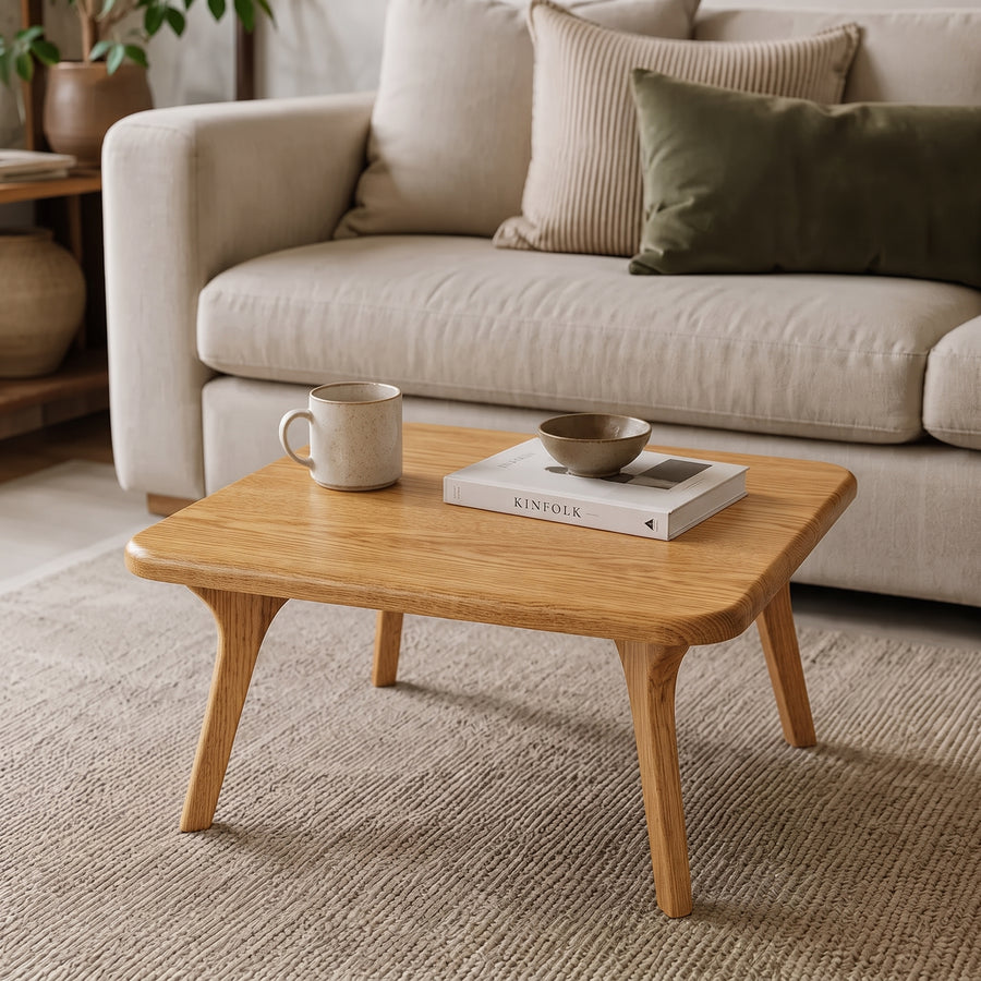 Sidney Square Wood Coffee Table Solid Oak Wood – Mid-Century Modern Design with tapered legs in a bright living room, styled with a ceramic mug, a book, and a small bowl in front of a light beige sofa.