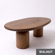 High-angle view of the Solen Oval Coffee Table – Beech Wood Modern Sculptural Design in a rich walnut finish with thick pillar legs.