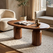 The Solen Oval Solid Wood Coffee Table – Oak & Walnut Sculptural Double Pedestal Design in a walnut finish styled in an organic modern living room.