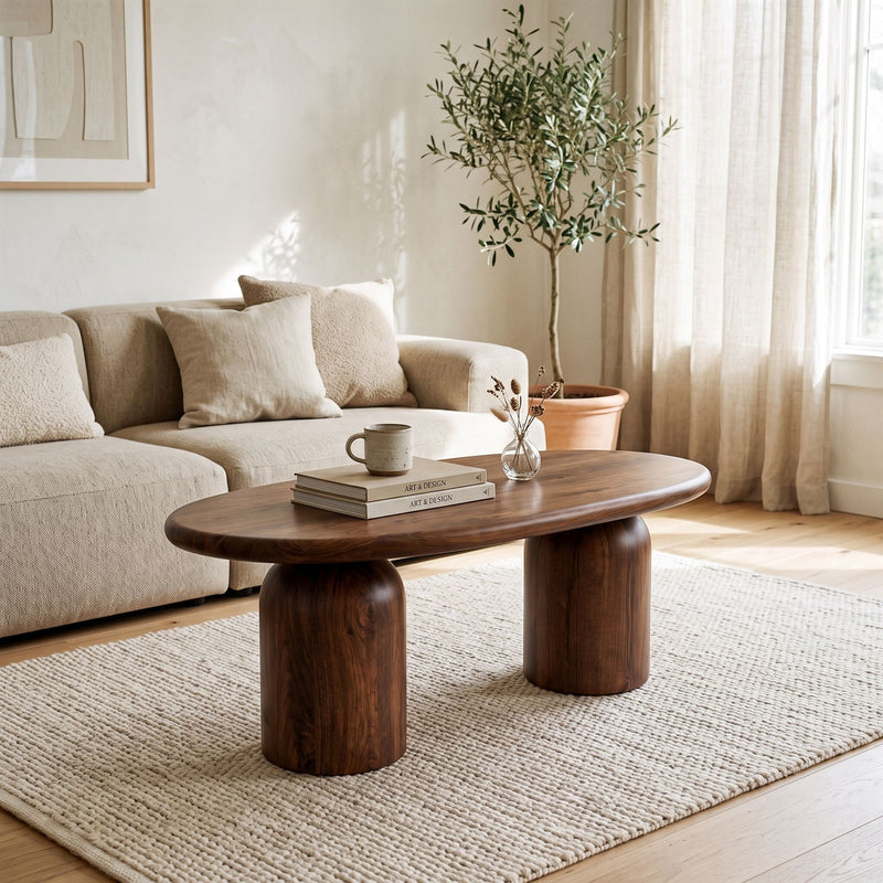 The Solen Oval Solid Wood Coffee Table – Oak & Walnut Sculptural Double Pedestal Design in a walnut finish styled in a bright, modern living room setup.