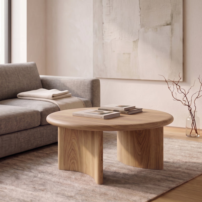 Soren Round Oak Coffee Table | Sculptural Scandinavian Modern Design with chunky block legs in a modern living room setting next to a gray sofa.