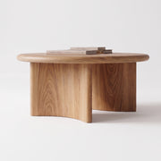 Soren Round Oak Coffee Table | Sculptural Scandinavian Modern Design with a thick, rounded top and a sculptural, blocky pedestal base, shown on a clean white studio background with a few books on top.