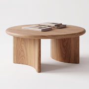 Soren Round Oak Coffee Table | Sculptural Scandinavian Modern Design with a natural oak finish, featuring two cylindrical legs and a curved front support, styled with three books on top against a clean white background.