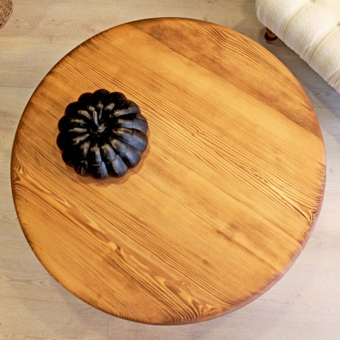 Side angle of the round coffee table, displaying its elegant, timeless design with a solid, well-balanced base.