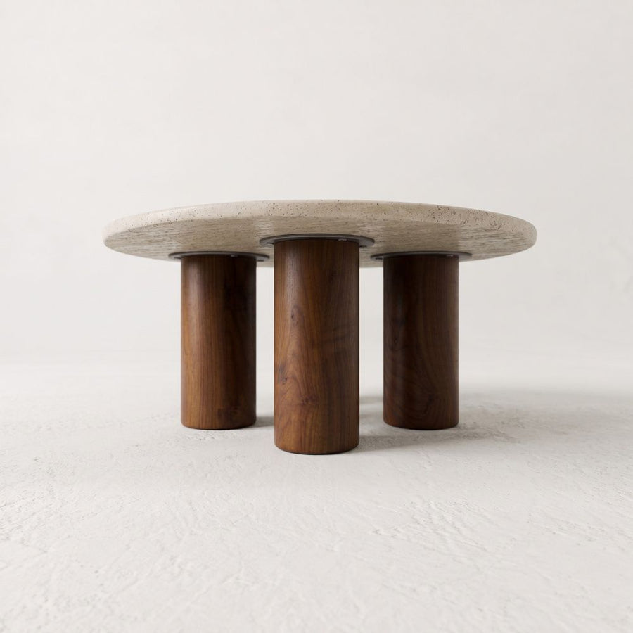 Low-Angle Studio View of Terra Round Travertine Coffee Table with Walnut Wood Triple Pedestal Base - Sculptural Modern Design by Tomruque