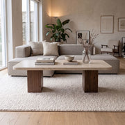 Wilder Rectangular Travertine Coffee Table with Solid Walnut Column Bases Styled on Textured Rug with Beige Sectional Sofa and Minimalist Decor in Modern Living Room