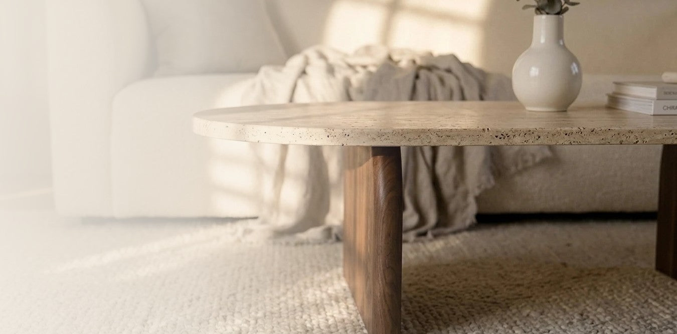 Travertine coffee table with a solid walnut leg in front of a cream sofa
