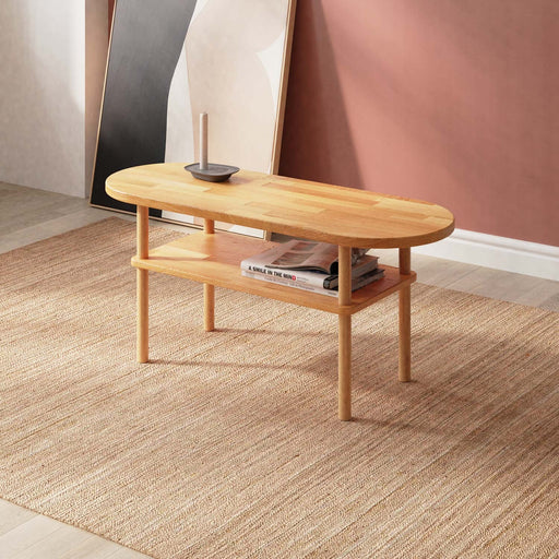 A side view of the Kennard beech wood oval coffee table featuring a minimalist design with smooth lines and a natural wood finish.