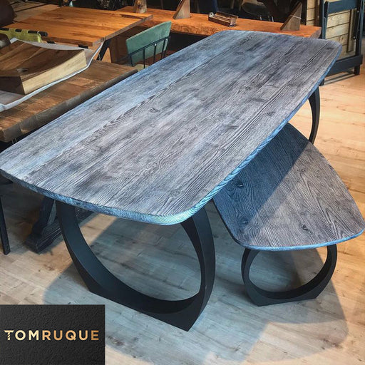 Gray dining table with a pine wood top and mid-century round metal legs, viewed in a modern dining room setting.