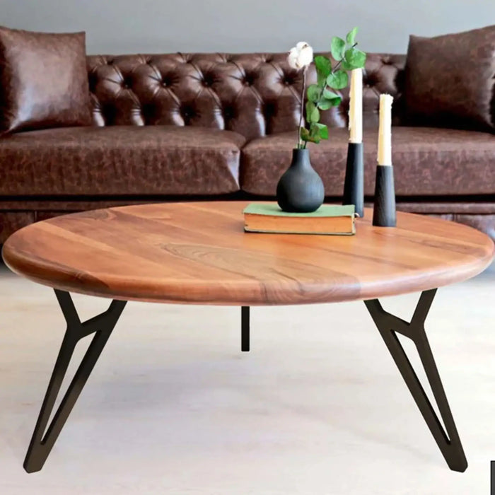 The round walnut coffee table in a cozy setting with décor accents – Displayed with books, a vase, and a cup of coffee, enhancing its stylish appeal.