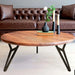 The round walnut coffee table in a cozy setting with décor accents – Displayed with books, a vase, and a cup of coffee, enhancing its stylish appeal.