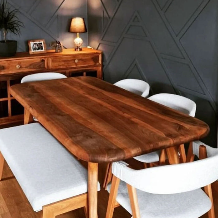 View of the Toledo wooden dining table with ambient lighting, highlighting the richness of the walnut finish.